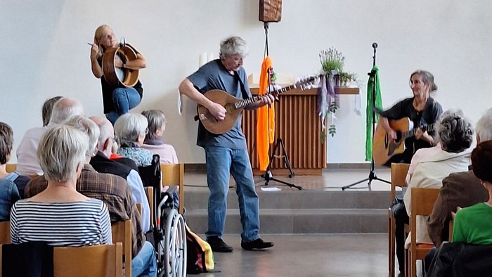 Mann und Frau mit Gitarre. Weitere Frau mit Bodhrán.