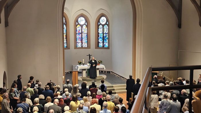 Pfarrer Anders gibt im Altarraum den Schlusssegen in der vollen Kirche.