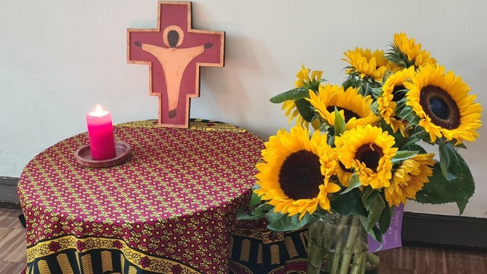 Ein Tisch mit Kerze, Kreuz und Sonnenblumen.