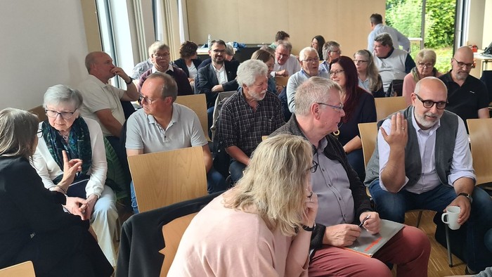 Gruppe von Personen, die in einem Klassenzimmer eine lebhafte Diskussion oder Besprechung führen.