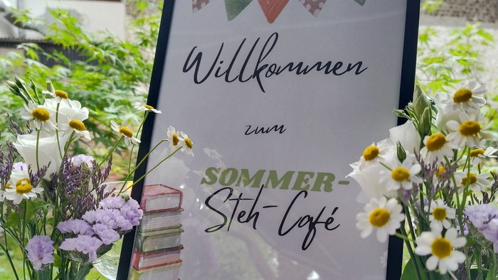 Staffelei mit einem Willkommensschild zum Sommer-Steh-Café der KÖB Antonius Alstaden