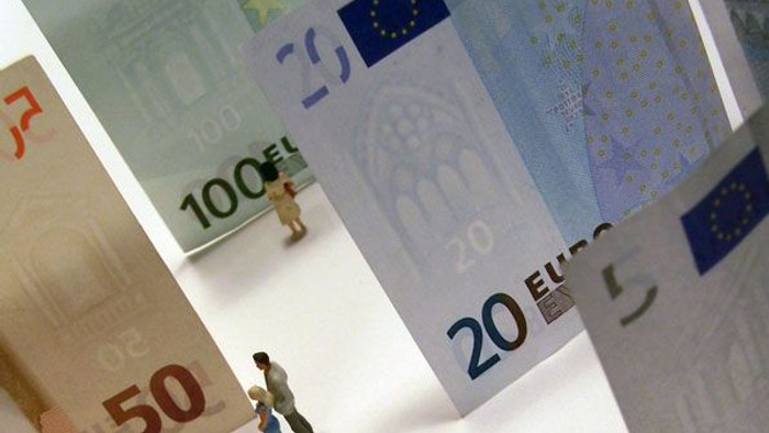 Kleine Figur steht zwischen Euro-Scheinen