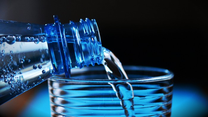 Wasser fließt aus einer Flasche in ein Glas