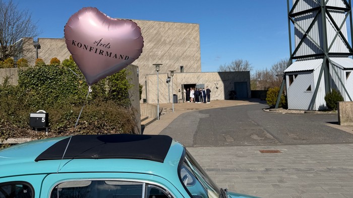En turkis vintagebil viser en hjerteformet ballon med teksten