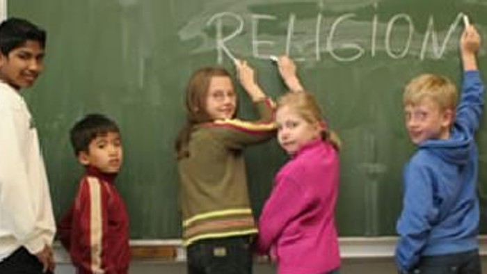 Kinder stehen vor Tafel mit dem Wort "Religion"