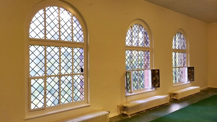 Drei bogenförmige Fenster mit farbigem Glas in gelbem Raum