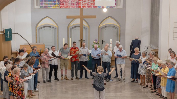 Gruppe von Menschen, die in einer Kirche Kerzen bei einer feierlichen Zeremonie oder Prozession halten.