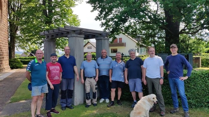 Das Bild zeigt Menschen vor einer Hecke an der Kirche Hagedorn.
