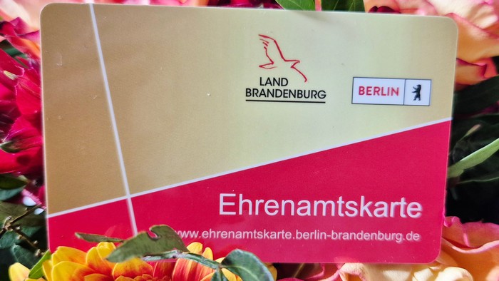 Eine Karte für Freiwilligen-Rabatte in Brandenburg und Berlin, umgeben von bunten Blumen.
