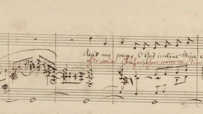 Das Bild zeigt eine handschriftliche Notenpartitur mit musikalischen Notationen und Text.
