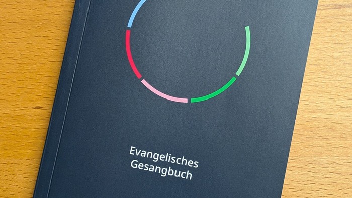 Evangelisches Gesangbuch mit buntem kreisförmigem Logo auf schwarzem Einband.