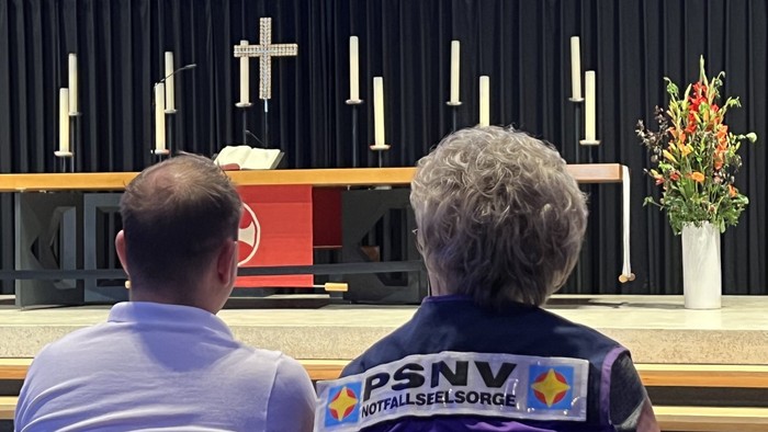 Zwei Menschen - von hinten zu sehen - blicken auf einen Altar
