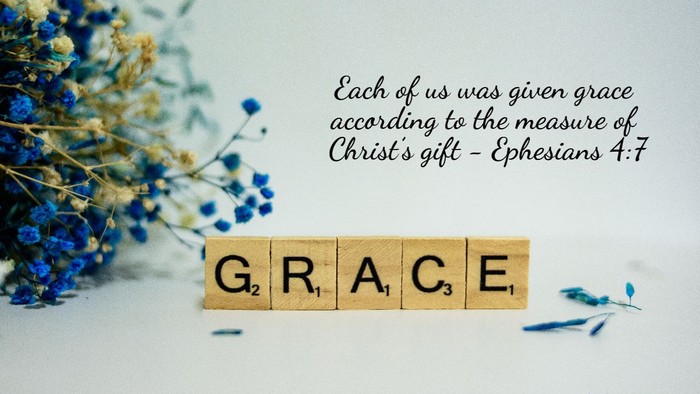 Scrabble tiles spell 'GRACE' with flowers and Bible verse text
