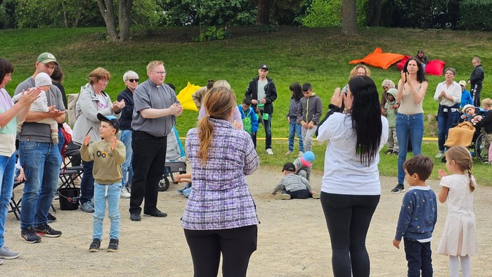 Ein lebhaftes Treffen im Freien mit Menschen, die in einem von Bäumen umgebenen Park Drachen steigen lassen.