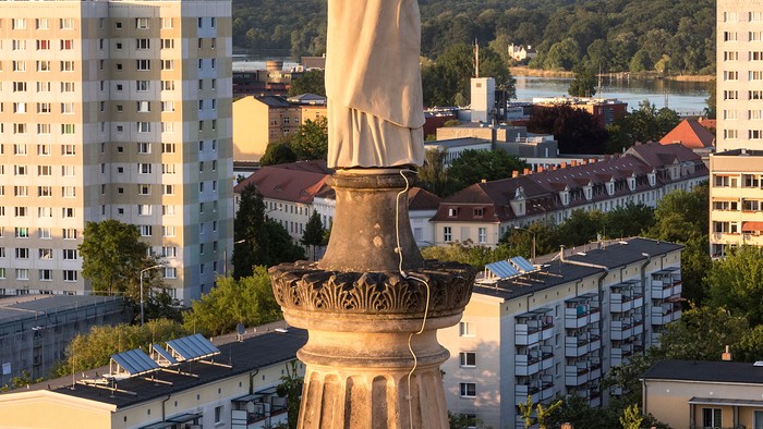 Große Engelsstatue auf hohem Sockel in Stadtlandschaft