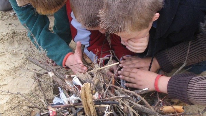 Kinder bauen am Strand ein Holzkonstrukt.