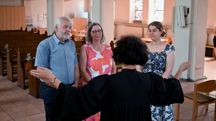 Eine Familie steht in der Kirche und wird von einer Pfarrerin gesegnet.