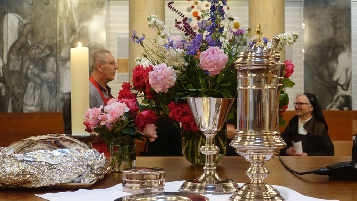 Elegante Altaraufstellung mit Blumen, Kerzen, Kelchen und religiösen Gefäßen während einer Zeremonie.