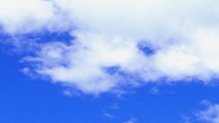Rolling green hills under blue sky with white clouds