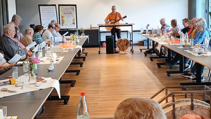Die Gruppe genießt live akustische Musik bei einem geselligen Beisammensein mit leichten Erfrischungen und angeregten Gesprächen.