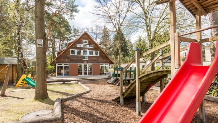 Im Garten eines Hauses befindet sich ein Spielplatz mit Rutsche und Klettergerüst.