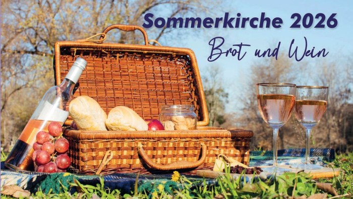 Brotkorb und Wein auf einer Picknickdecke im Grünen. Darüber das Motto der diesjährigen Sommerkirche