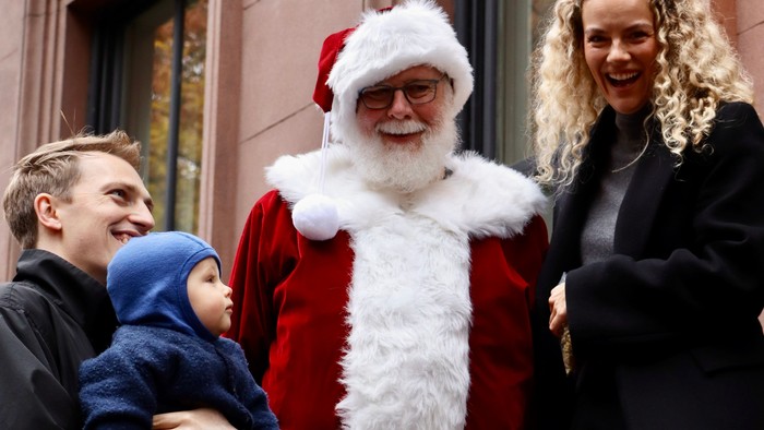Familie poserer med julemanden uden for en bygning