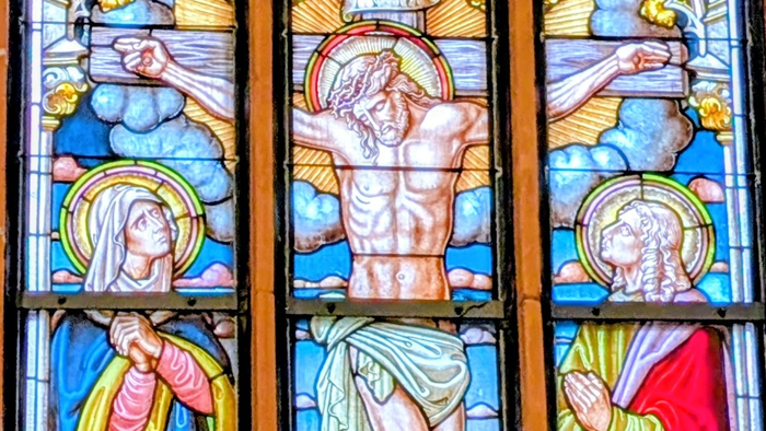 Buntglasfenster mit Szenen der Kreuzigung Jesu und biblischen Figuren in lebendiger, detailreicher Kunst.