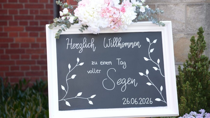 eine mit Blumen geschmückte Tafel mit der Aufschrift: Herzlich willkommen zu einem Tag voller Segen