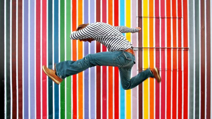 Ein Skateboarder führt einen Trick vor einer farbenfrohen Wand aus.