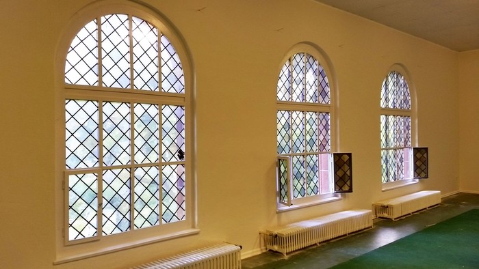 Drei bogenförmige Fenster mit farbigem Glas in gelbem Raum
