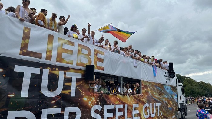 Ein Truck mit Regenbogenfahne, Menschen und der Aufschrift: