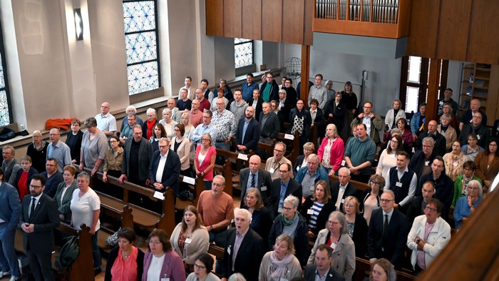 Das Bild zeigt den Innenraum einer Kirche. Sie ist voll besetzt. Die Menschen stehen und singen. Im Hintergrund ist die Orgel zu sehen.