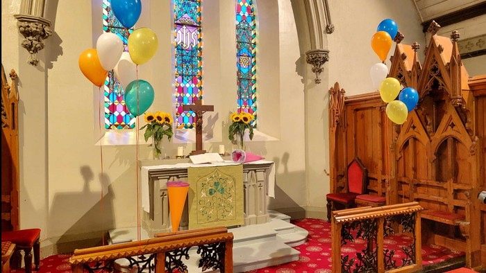 Farbenfrohe Ballons in Kirche, Altar mit Blumen, bunte Fenster