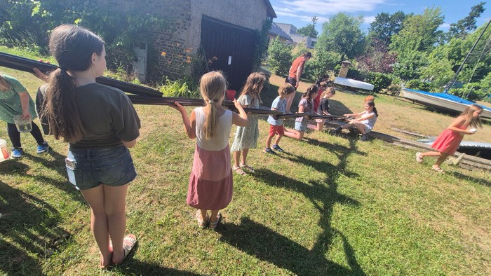 Eine Gruppe von Menschen spielt mit einer großen Frisbee auf einer grasbewachsenen Fläche im Freien.