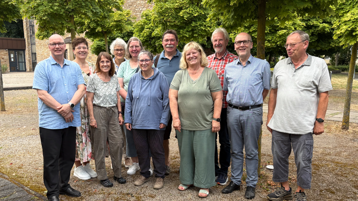 Eine Gruppe von Menschen steht auf einem Kirchvorplatz