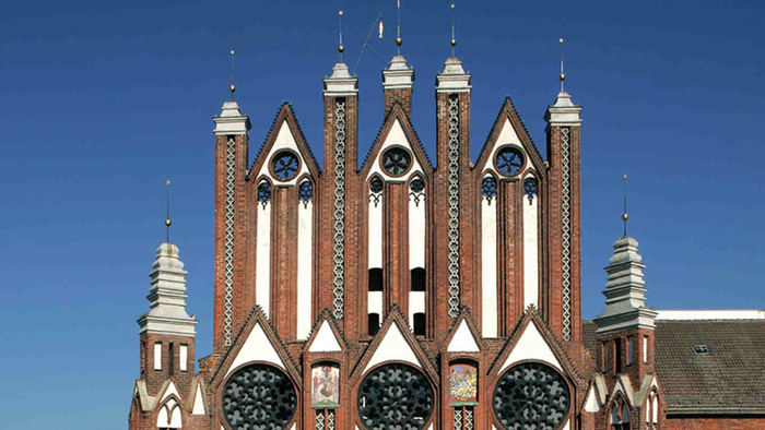 Historisches Backsteingebäude mit aufwendiger neogotischer Architektur, gekennzeichnet durch Spitzbögen und dekorative Türmchen.