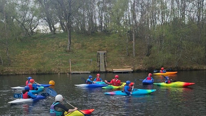 Group paddling colorful kayaks on a calm river surrounded by lush greenery.