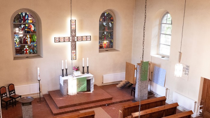 Kleine Kirche mit Holzgestühl und zwei buntverglasten Fenstern