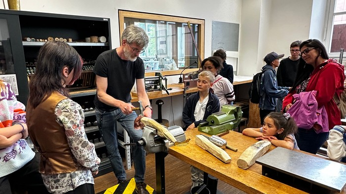 Die Leute versammeln sich um eine Küchenarbeitsplatte und lernen in einem Workshop, wie man Essen zubereitet.