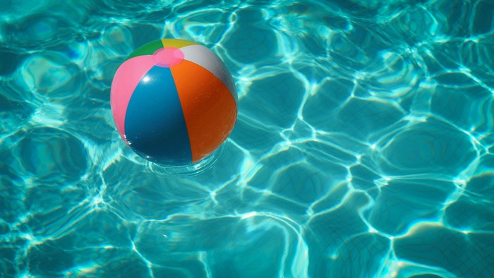 Bunter Strandball, der in funkelnd klarem Schwimmbadwasser treibt.