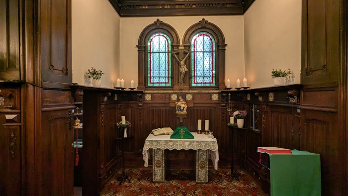 Elegante Kapelle mit hölzernem Altar, Buntglasfenstern und religiösen Verzierungen.