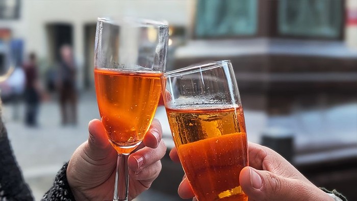 Zwei Gläser mit orangefarbenem Getränk stoßen an