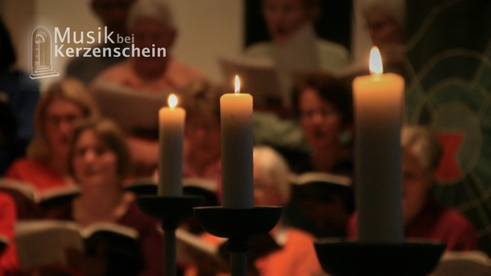 Drei brennende Kerzen stehen im Vordergrund, während im Hintergrund ein Chor im Kerzenschein aus Notenheften singt. Oben links ist das Logo der Veranstaltungsreihe „Musik bei Kerzenschein“ zu sehen.