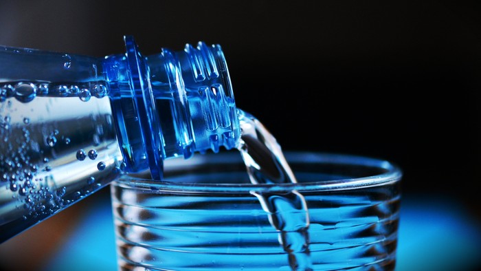 Wasser fließt aus einer Flasche in ein Glas