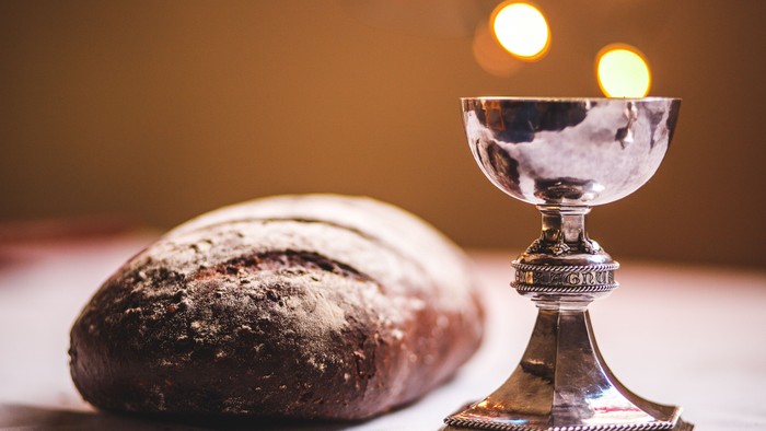 A silver chalice and a loaf of bread on a table