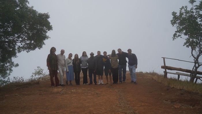 Eine Gruppe von elf Personen steht gemeinsam auf einem Aussichtspunkt. Dichter Nebel verdeckt im Hintergrund fast vollständig die Berglandschaft.