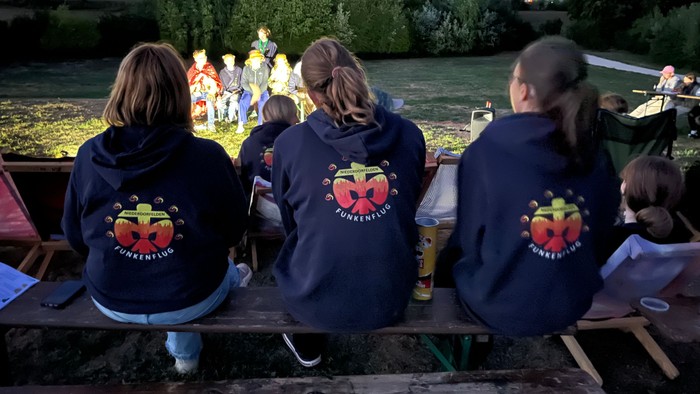 Zuschauer beim Bunten Abend mit Aufführung im Hintergrund