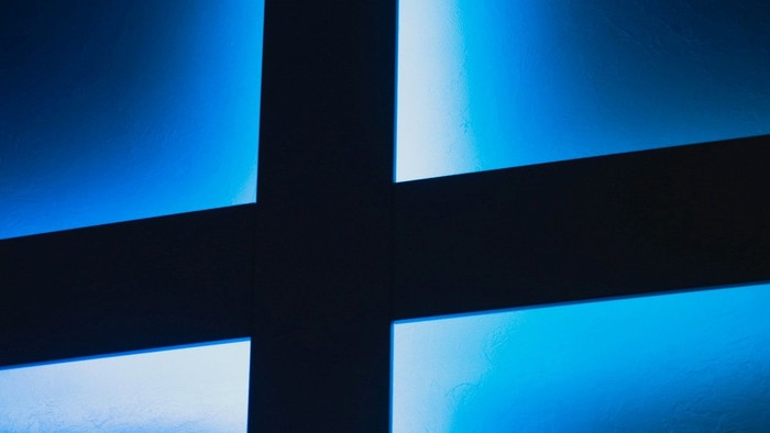 A silhouetted cross illuminated by blue light against a dark background.
