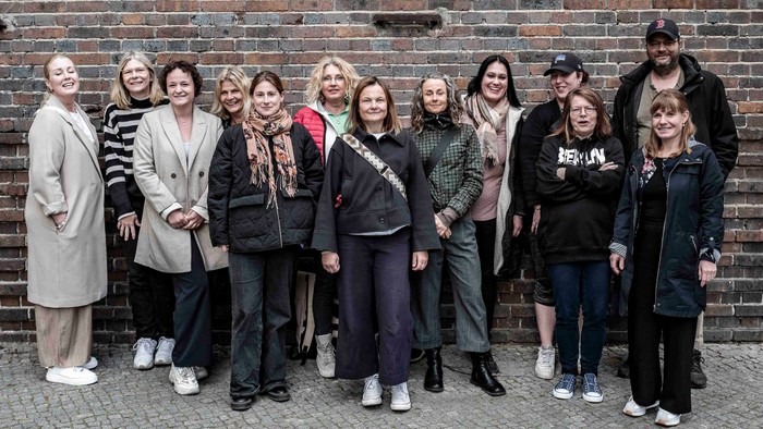 Gruppe von Personen, die gemeinsam vor einer Ziegelsteinwand posieren